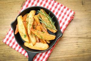 gajos de patata en un plato con hierba de romero, cocinando patatas fritas o patatas fritas - vista superior foto