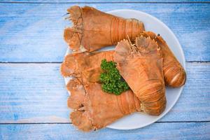 Flathead lobster shrimps served on white plate, Fresh slipper lobster flathead boiled cooking with parsley - top view photo