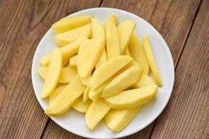 fresh raw potato wedges, chopped potatoes for cooked food on white plate photo