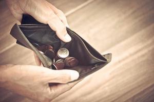 Coin in wallet and debt management concept - Empty wallet in the hands of an elderly man Poverty in retirement concept photo