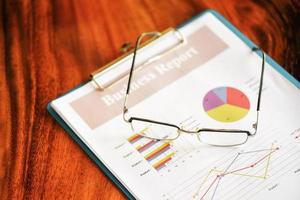 anteojos en gráficos de diagrama documento de papel de gráfico de negocios trabajando en la oficina - concepto de plan de informe de negocios foto