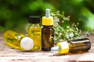 aceites esenciales naturales sobre fondo de madera y hojas verdes - aroma de botellas de aceite de hierbas de aromaterapia foto