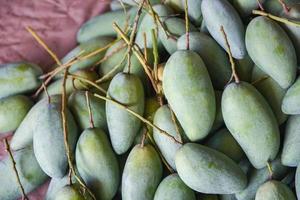 Green mango for sale in the fruit market in Thailand - Fresh raw mango texture background harvest from tree agriculture asian photo