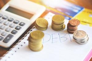 Calculator and coin stack on notebook paper with debt credit card at the office financial counting debt management concept photo