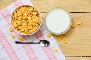 tazón de copos de maíz y cereales para el desayuno con leche sobre fondo de madera para una comida saludable