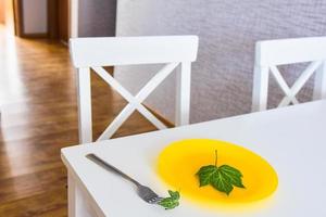 Kitchen white table with with wild green leaf on yellow plate. Extreme diet and slimming concept. photo