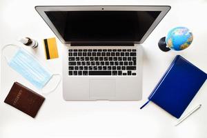 Mock up display of laptop on white wooden table for Summer Holiday Vacation background concept. Flat lay top view of Notebook Laptop, camera, global pandemic accessories photo