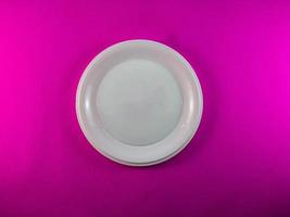 White plate on bright pink background photo