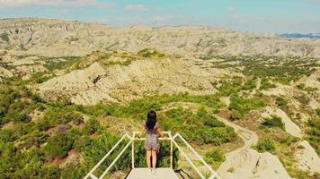 jonge vrouw staat op gezichtspunt met schilderachtige bergen in zicht. vrouw staart naar de natuur in de verte met het prachtige landschap van georgië. geniet van een reisbestemming buiten in het nationale park van Vashlovani.