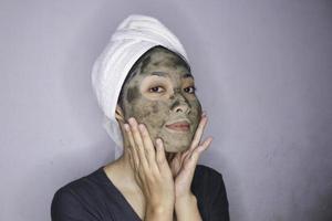 sonríe a las mujeres asiáticas sonriendo cuando usa una máscara facial de belleza foto