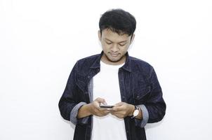 Smile and happy face of Young Asian man when playing game at phone in hand. photo