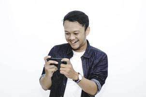 Smile and happy face of Young Asian man when playing game at phone in hand. photo