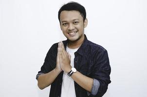 Young Asian man wearing give greeting hands. Indonesian man on grey background. photo