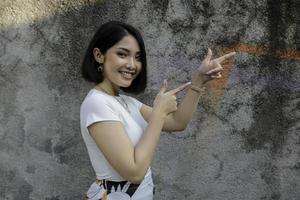 Happy and smile face with smile of young Asian girl with hand point on empty space. photo