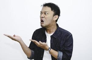 Angry and hate face of young Asian man in shirt with hand point on empty space. photo