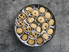 An overhead photo of a tin can of Danish butter cookies, shot from above on a light background texture with a place for text