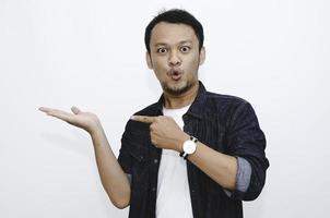 Young asian man is surprised and shouting wow with pointing right with his hand isolated on gray background. photo