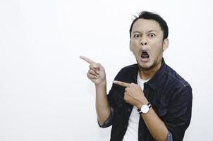 Young asian man is surprised and shouting wow with pointing right with his hand isolated on gray background. photo