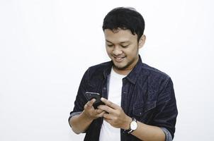 Smile and happy face of Young Asian man when playing game at phone in hand. photo