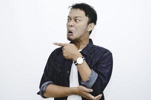 Angry and hate face of young Asian man in shirt with hand point on empty space. photo