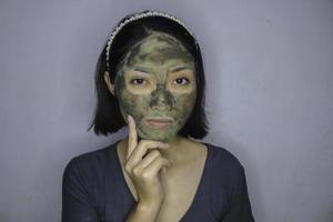 una mujer asiática estaba pensando y soñando despierto cuando usa una máscara facial de belleza foto