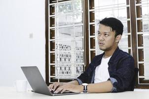 Young Asian man feeling stress and confuse when work laptop on table. photo