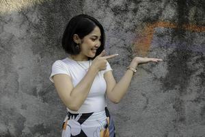 Happy and smile face with smile of young Asian girl with hand point on empty space. photo