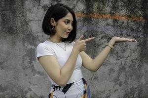 Happy and smile face with smile of young Asian girl with hand point on empty space. photo