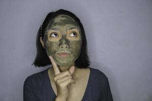 una mujer asiática estaba pensando y soñando despierto cuando usa una máscara facial de belleza foto