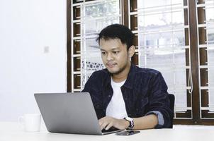 Young Asian man feeling serious when work laptop on table. photo