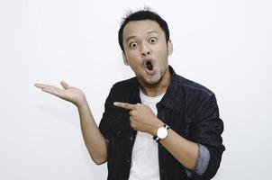 Young asian man is surprised and shouting wow with pointing right with his hand isolated on gray background. photo