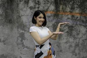 Happy and smile face with smile of young Asian girl with hand point on empty space. photo