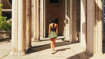 Back view caucasian beautiful woman in slow motion walk and admire historical landmark in sunny summer day. Female influencer on travel holiday video