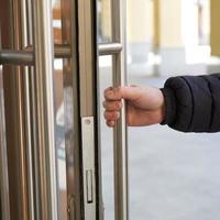 Man takes door handle with his hand and opens door. Place of accumulation of coronavirus, COVID-19 photo