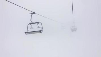 People in ski resort chair lift in stormy winter conditions.Bad visibility and weather in ski resort concept.