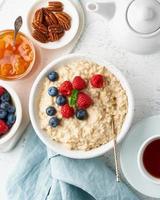 Oatmeal porridge with blueberry, raspberries, jam, vertical, top view. Breakfast with berries photo