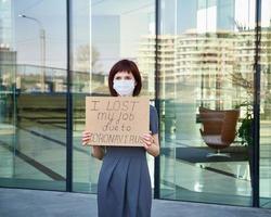 mujer con máscara sostiene el cartel de que perdí mi trabajo debido al concepto de coronavirus de pérdida de trabajo debido a covid-19 foto