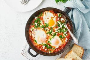 Shakshouka, eggs poached in sauce of tomatoes, olive oil. Mediterranean cuisine. photo