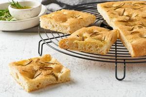 Focaccia, pizza, italian flat bread with rosemary and olive oil on grid photo