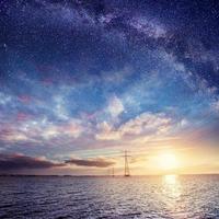 Power lines over water at night. Mysterious starry sky. Cumulus photo