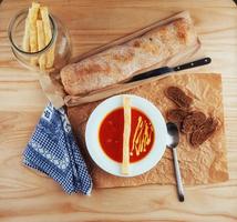 Fresh tomato soup in a white mask with bread baguette photo