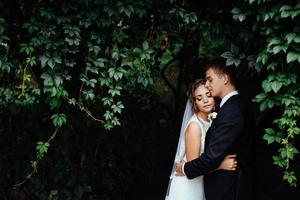 Young bride hugging her groom in beautiful park photo