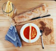 Fresh tomato soup in a white mask with bread baguette photo