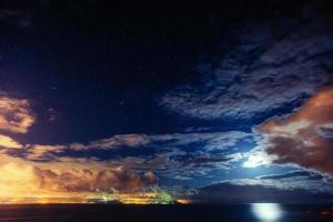 The starry sky above rocky mountains. Fantastic lighting city th photo