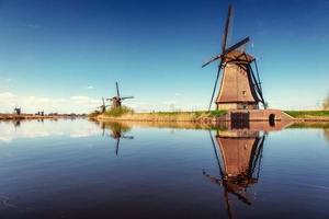 Colorful spring day with traditional Dutch windmills canal in Ro photo