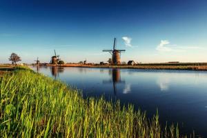 Colorful spring day with traditional Dutch windmills canal in Ro photo