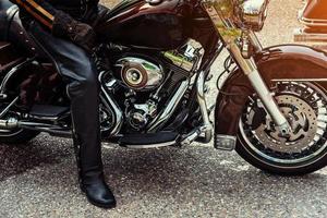 Biker in black boots sitting on a motorcycle photo