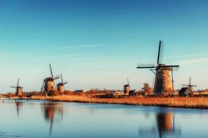 Colorful spring day with traditional Dutch windmills canal in Ro photo