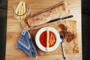 Fresh tomato soup in a white mask with bread baguette photo