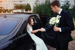 Happy bride and groom near car. photo